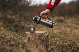 themed trip man pours hot drink into thermos mug wooden log 117255 652